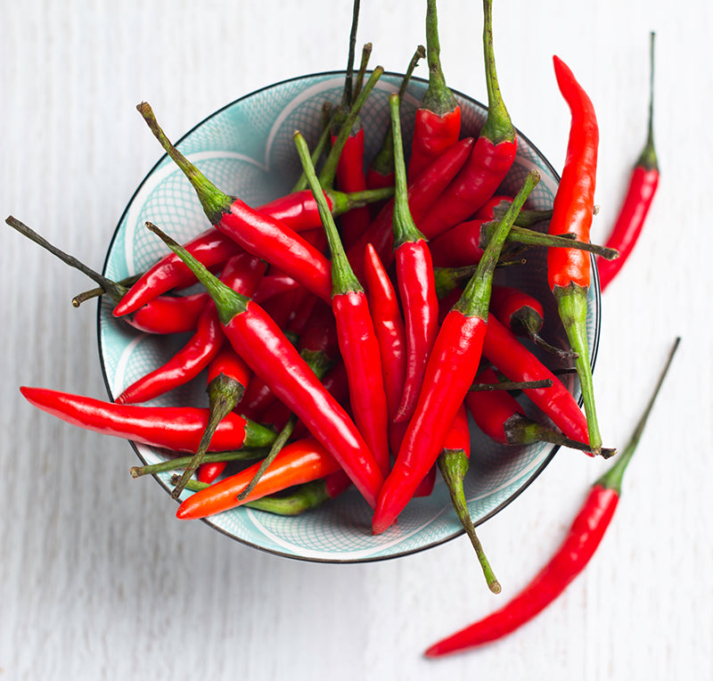Bowl of fresh red Thai Hot Peppers, harvested from Thai Hot Pepper Seeds, perfect for adding heat to Sichuan and Thai cooking.