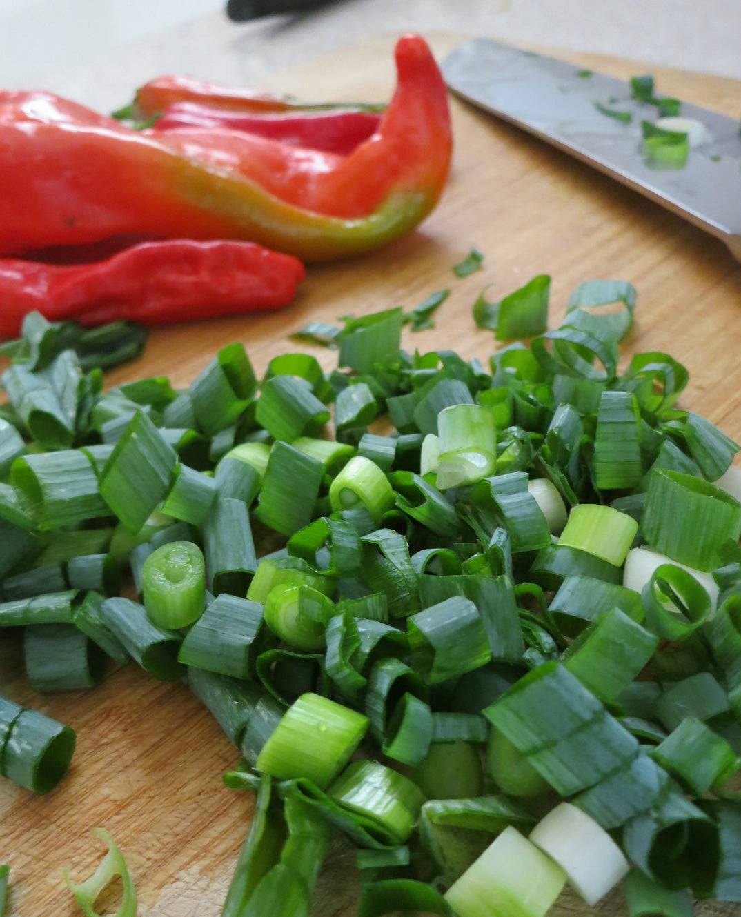 Freshly chopped White Lisbon bunching onions on a cutting board, perfect for adding mild flavor to salads, soups, and stir-fries.