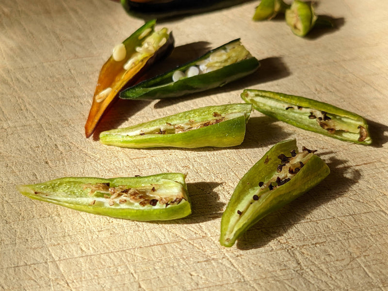 A close-up of sliced green jalapeno peppers with black seeds, highlighting their spicy interior and vibrant green color.