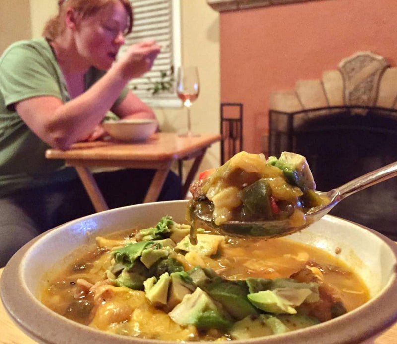 Vegetarian Green Chili Stew - a woman eating a bowl of the stew