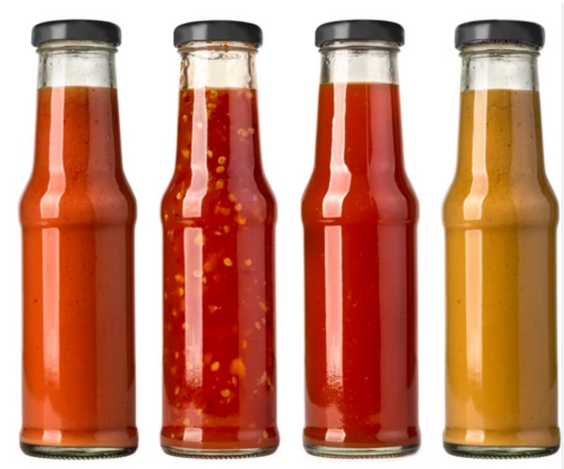 Fermented Hot Sauce Recipe - with Carolina Reapers: Four glass bottles of fermented hot sauce with vibrant red and yellow hues, featuring Carolina Reapers, showcasing the spicy, tangy flavors of homemade fermented hot sauce.