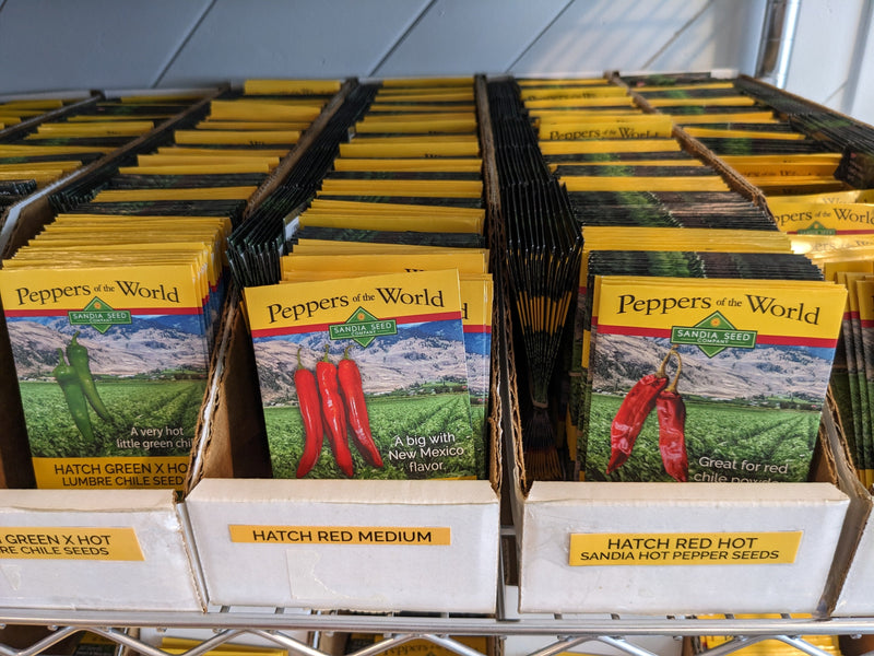 A diagram of seed packets for growing peppers, including hot and medium varieties, displayed on a store shelf for gardening and agricultural purposes.