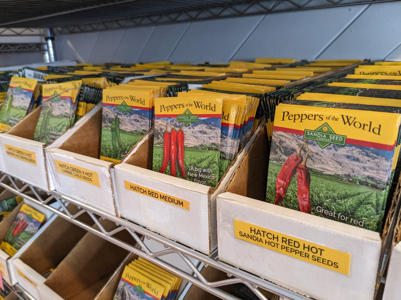 A diagram of seed packets for wholesale pepper seeds, including hot peppers, red medium, and other varieties, displayed on metal shelving for gardening and agricultural supply.