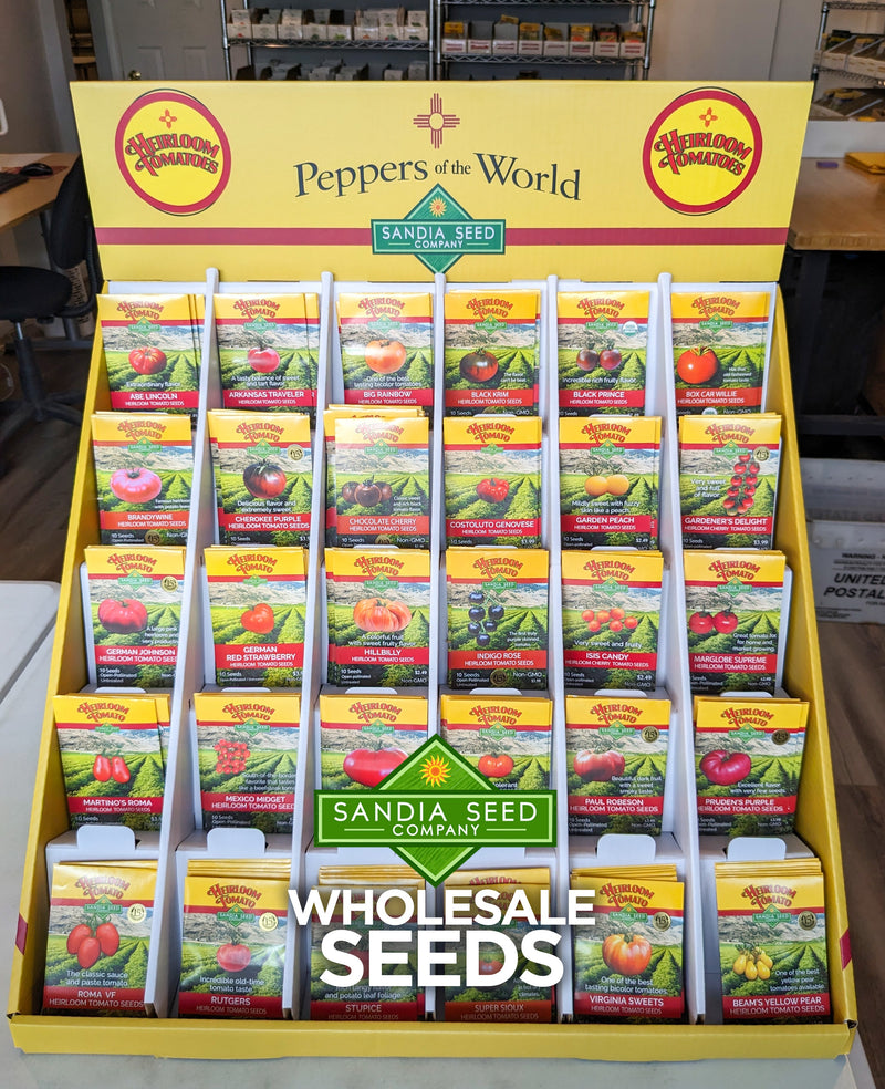 An illustration of a colorful seed display stand featuring heirloom tomato seeds from Sandia Seed Company, showcasing various seed packets with vibrant images and descriptions.