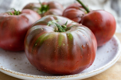 Ripe Black Krim tomatoes on a speckled ceramic plate