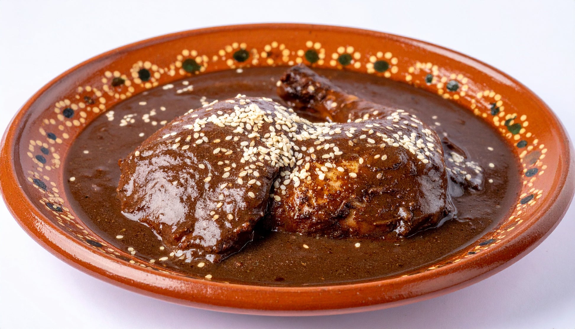 Authentic mole poblano with chicken showing complex sauce texture and sesame seeds in handmade clay cazuela isolated background